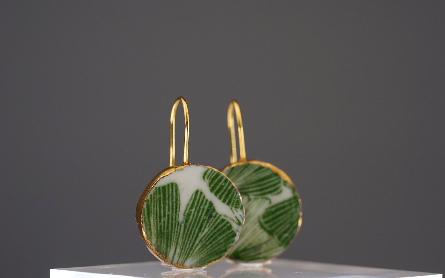 Diese Ohrringe zeichnen sich durch ein einzigartiges Ginkgo-Motiv in lebendigem Grün aus, das kunstvoll auf feinstem Porzellan gestaltet ist. Das beidseitige Design sorgt für eine harmonische Ästhetik, egal aus welchem Blickwinkel.