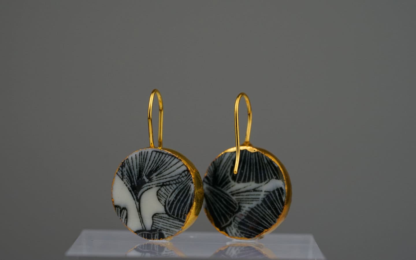 Diese Ohrringe kombinieren das kontrastreiche Schwarz-Weiß eines Ginkgo-Motivs mit einem edlen Rahmen aus 24-karätigem Gold.
