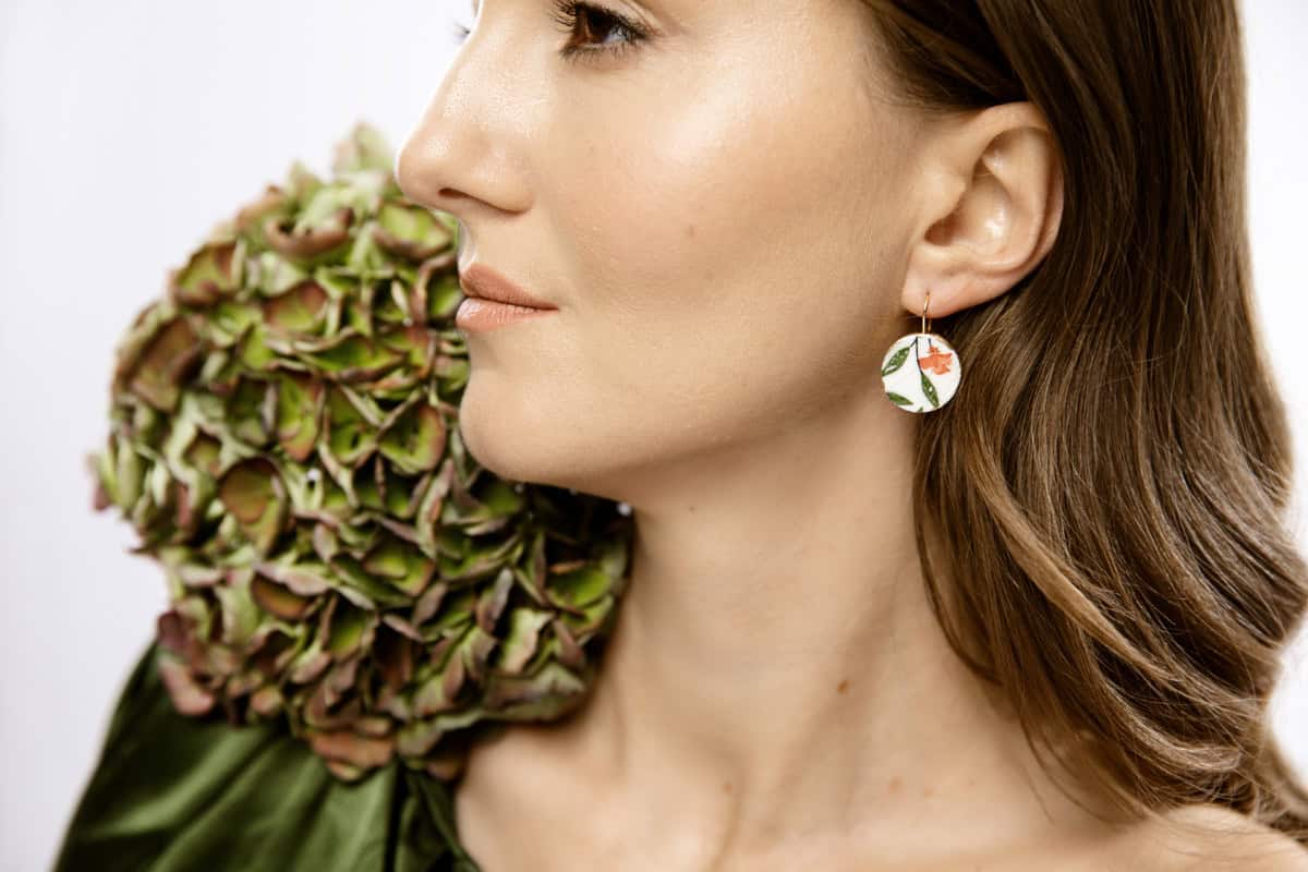 Eine tiefrote, getupfte Rose mit zarten grünen Blättern, als wäre sie gerade frisch gepflückt. Sie verkörpert Eleganz und die zeitlose Schönheit klassischer Blumenmalerei.